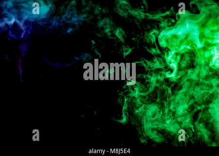 Dense multicolored smoke of green and   blue  colors on a black isolated background. Background of smoke vape Stock Photo