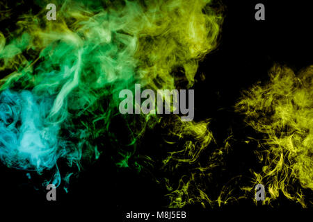 Dense multicolored smoke of green and   blue  colors on a black isolated background. Background of smoke vape Stock Photo