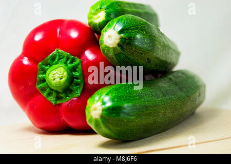 soft focus of fresh red pepper and green zucchini on a white background - capsicum, cocurbita pepo Stock Photo