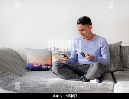 Young man uses smartphone and credit card for online purchase Stock Photo