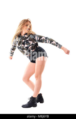 Smiling passionate joyful woman dancing with flowing tousled hair wearing camouflage jacket. Full body isolated on white background. Stock Photo