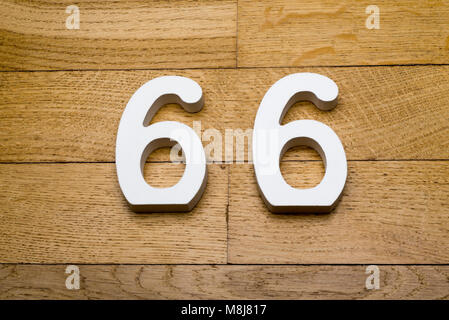 The numbers sixty-six on wooden parquet floor in the background. Stock Photo