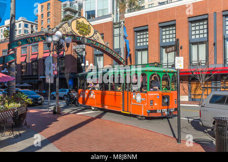 SAN DIEGO, CALIFORNIA, USA - Green and Orange Old Town Trolley city tour vehicle passing under the entrance arch to the historic Gaslamp Quarter. Stock Photo