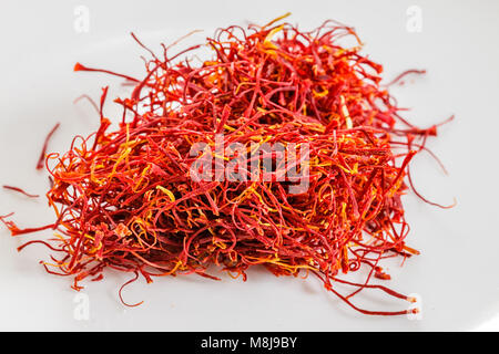 Macro photograph of crimson threads of the spice saffron isolated on white background.  The flower stigmas and styles are the expensive spice. Stock Photo