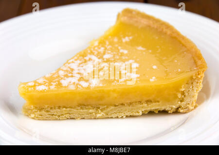 Lemon tart slice on a white plate with a shallow depth of field Stock Photo