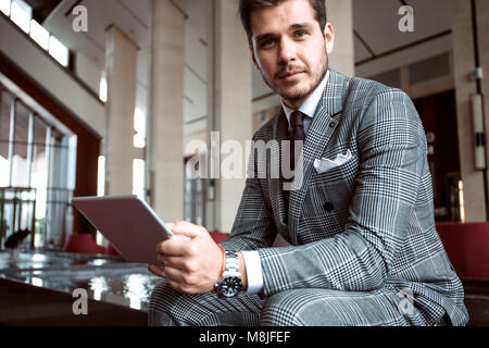 Smartly dressed businessman, smiling in modern office Stock Photo