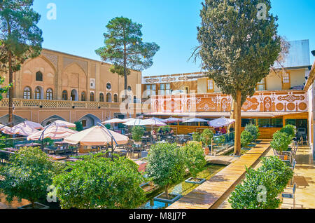 ISFAHAN, IRAN - OCTOBER 20,2017: The courtyard of historical mansion with shady garden is served as restaurant of traditional cuisine, located in Julf Stock Photo