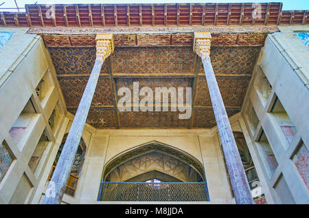 ISFAHAN, IRAN - OCTOBER 20, 2017: The  carved wooden ceiling and slender pillars of the porch of Hasht Behesht Palace, famous for its outstanding deco Stock Photo