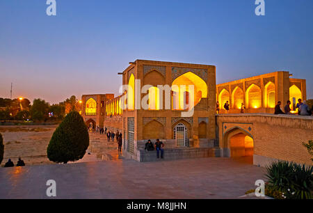 ISFAHAN, IRAN - OCTOBER 20, 2017: The parks along the Zayandeh river and medieval bridges across it are very popular places for the evening walks, suc Stock Photo