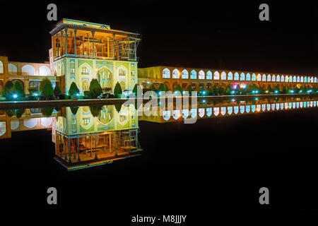 The turned off fountain in the middle of Naqsh-e Jahan square serves as the mirror, reflecting  bright building of Qapu palace with long arched galler Stock Photo