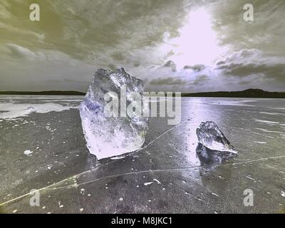 Beautiful epic ice crystal in the frozen bay.  Sun rays reflection in cracks, backlight  of the setting sun. Stock Photo