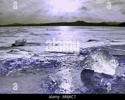 Beautiful epic ice crystal in the frozen bay.  Sun rays reflection in cracks, backlight  of the setting sun. Stock Photo