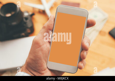 Travel app for mobile phone mock up screen, overhead view of male hand using smartphone with blank screen as copy space Stock Photo