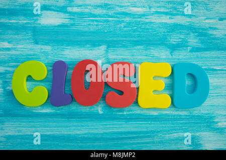 Closed in capital letters on blue colour wash wood background Stock Photo