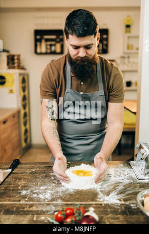 Homemade pasta cooking, bearded chef preparing dough on wooden kitchen table Stock Photo