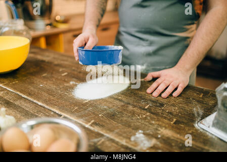 Fresh pasta cooking, male chef in apron on kitchen. Man preparing dough on wooden table Stock Photo