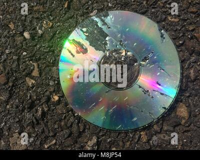 Damaged CD laying on the road Stock Photo