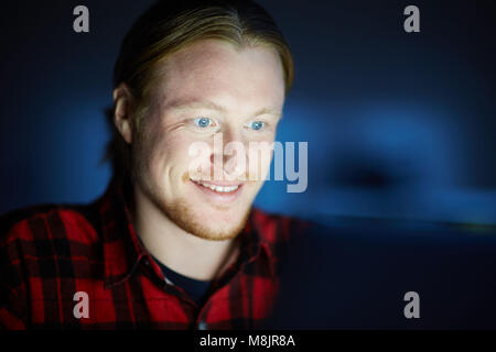 Smiling man sitting in front of the computer Stock Photo