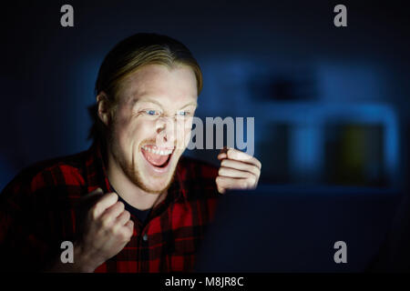 Satisfied man watching something on computer till night Stock Photo