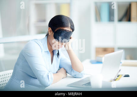Businesswoman in mask sleeping at her workplace Stock Photo