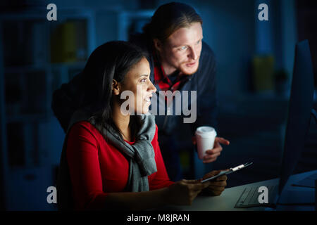 Businesspeople working in team till night. They are using computer for work Stock Photo