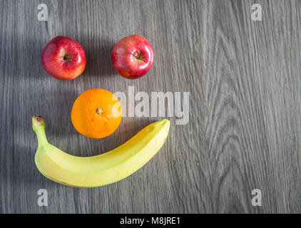 Different kinds of fruit including apples, oranges and bananas arranged into a smiling face to encourage children to eat healthily. Stock Photo