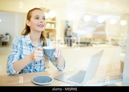 Young woman drinking coffee at the table at coffee shop Stock Photo