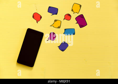 Smartphone on yellow background with text bubbles around. Messaging, texting and connection concept Stock Photo