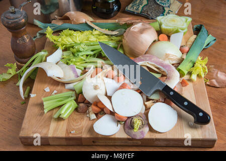 Peelings from vegetables and a cooks knife sit on a cutting board. Stock Photo