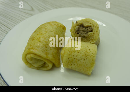 Hot folded pancakes with beef and greens on wooden background Stock Photo