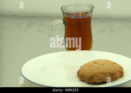 Tea cup with green tea, dried tea leaves and fresh fragrant Jasmine flower and biscuits on white background. Top view composition Stock Photo