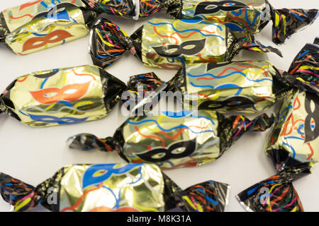 Colorful confetti candy in the form of carnival mask on pink background Stock Photo