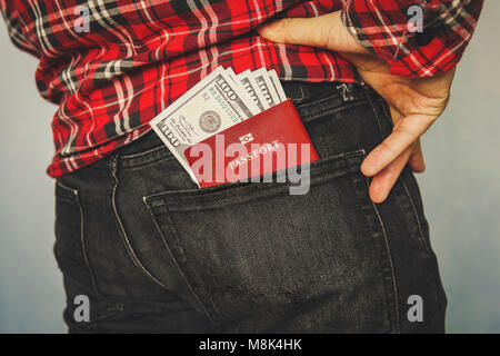red unidentified passport in a pocket of jeans. pocket money for personal expenses during trips and travel. Currency exchange. Stock Photo