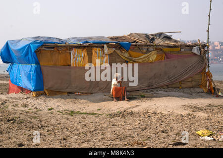 VARANASI, INDIA. February 28, 2017: The hermit, a sadhu, sits meditating on the opposite of the Varanasi banks of the Holy river Ganges Stock Photo