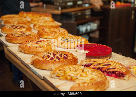 Different types of pies in pastry shop on the wooden display. Selective focus, space for text. Stock Photo
