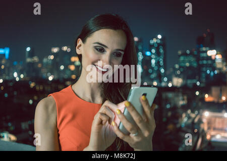 Woman using phone for social media in urban setting Stock Photo