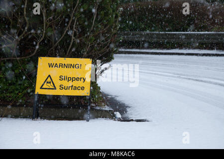 A warning sign in a car park in Fife Scotland, warning about a a slippery surface with snow on the ground. Stock Photo