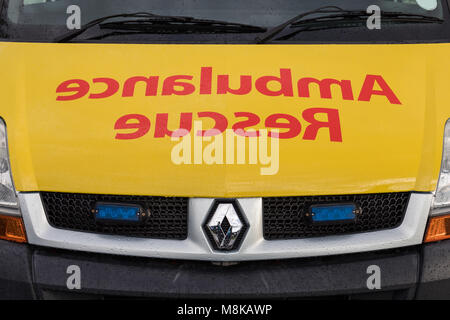 The word Ambulance Rescue written frontbackwards on the front of ambulance car Stock Photo