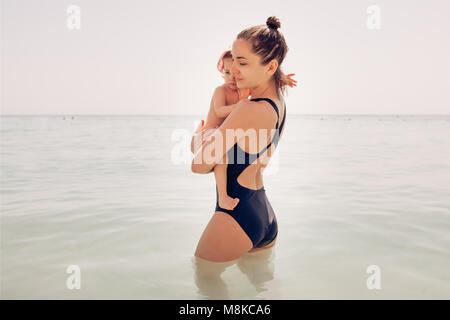 Mom with a little daughter are waist-deep in the sea water. Summer Stock Photo