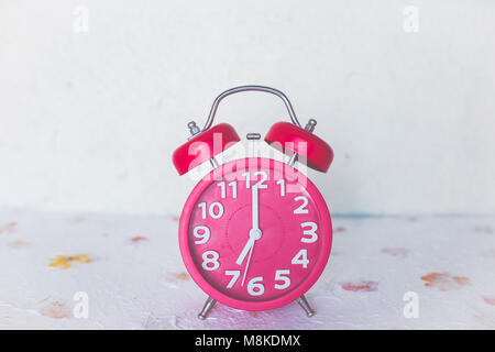 Red alarm clock on leaf ground with soft filter image Stock Photo