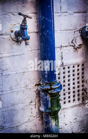 Corroded drainpipe and exterior water tap Stock Photo