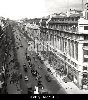 Historical picture from 1947 of Kingsway, London, WC2, England, UK ,with vehicles parked in the middle and side of the road. in the picture on the right is the Stoll Theatre - the former London Opera House - showing the musical, Oklahoma. Also seen is the passsenger entrance to the underground Aldwych tramway station, part of the Kingsway Tramway. Stock Photo