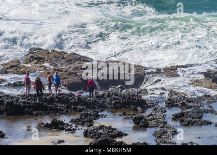 Tourists brave crashing waves to explore Thor's Well at Cape Perpetua Scenic Area, Oregon Stock Photo