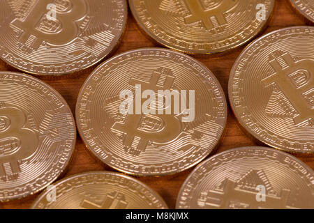 several golden bitcoins on top of wooden table. Stock Photo
