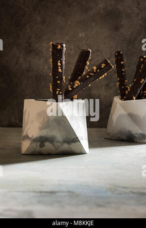 Wafer Chocolate Rolls with almonds, in geometric concrete bowl, on grunge background. Stock Photo