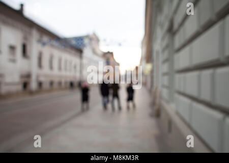 Abstract blurred background of a pedestrian street in the city. Light photo with blurred silhouettes of people walking around the city. Stock Photo