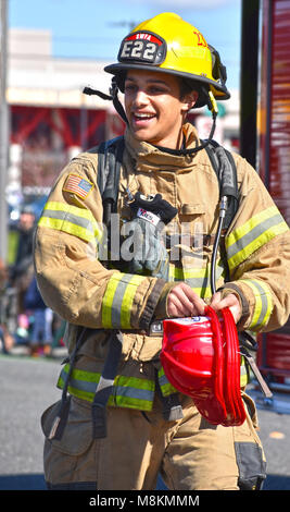 A fireman in the St. Patrick's Day Parade in Bellingham, Washington on March 17, 2018.  The fireman is giving out red fire hats. Stock Photo