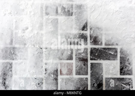 Tiled pavement covered with snow. Footprints on slippery surface. Abstract winter texture. Copyspace for text Stock Photo