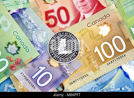 MONTREAL, CANADA - MARCH 10, 2018: Silver Litecoin cryptocurrency on canadian bank notes. Stock Photo