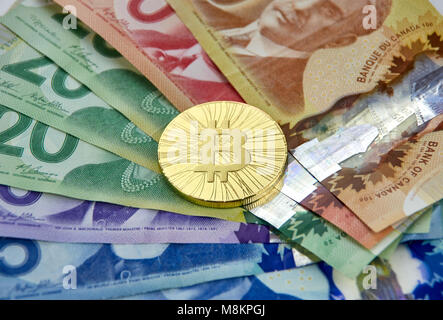 MONTREAL, CANADA - MARCH 10, 2018: Gold bitcoin cryptocurrency on canadian bank notes Stock Photo